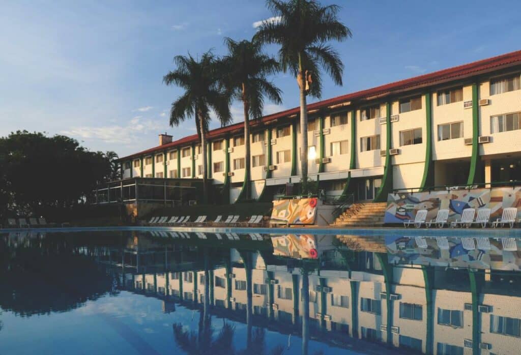 Piscina ampla no Eldorado Atibaia Eco Resort durante o dia e ao fundo a hospedagem. Representa pousadas em Atibaia.