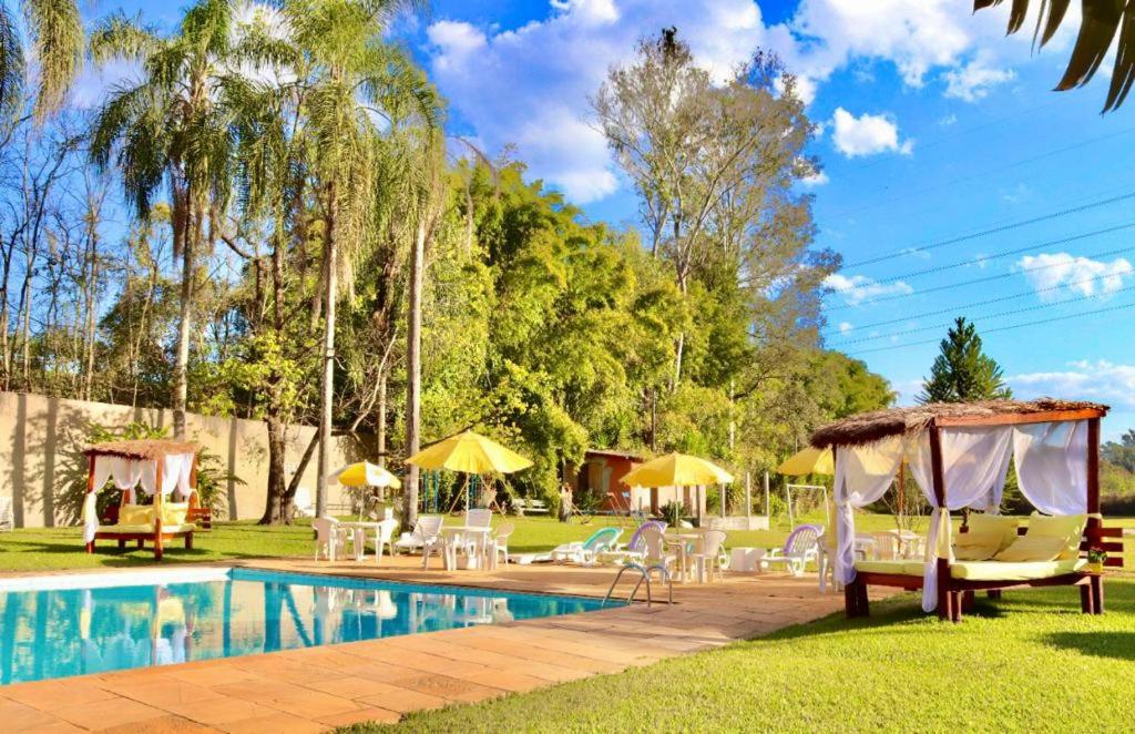 Área externa com piscina do Estância Canaã durante o dia, com cadeiras do lado direito. Representa hotéis em Atibaia.