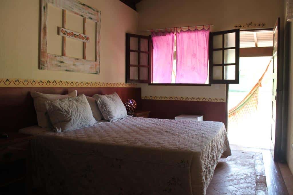 Quarto do hotel Fazenda Coronel Jacinto, com cama de casal do lado esquerdo.