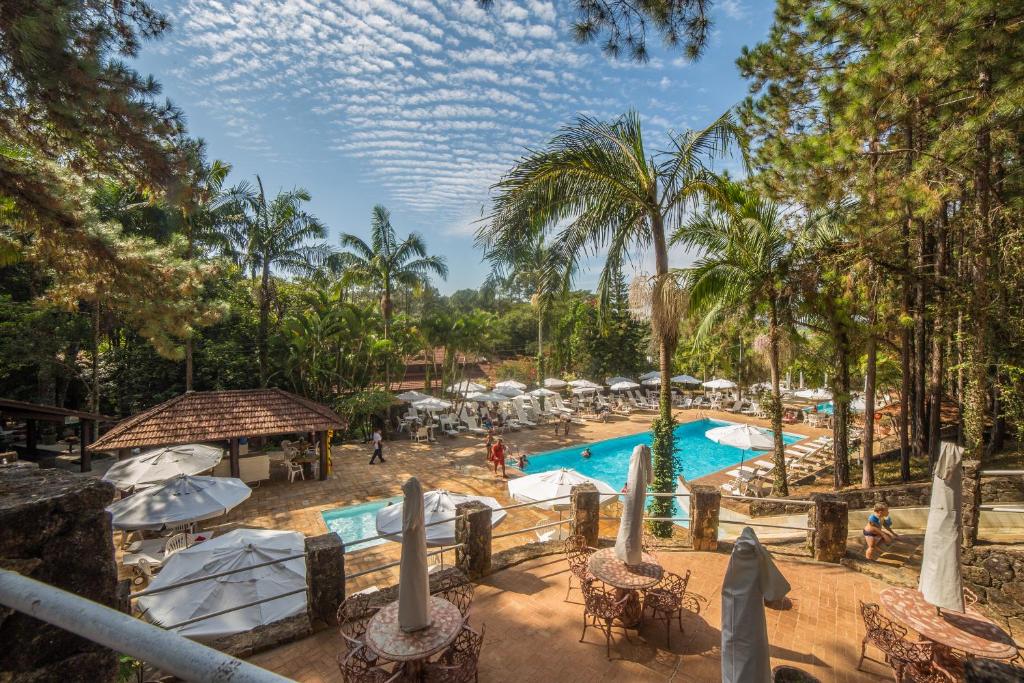 Piscina do Hotel Estância Atibainha durante o dia, com coqueiros em volta. Representa hotéis em Atibaia.