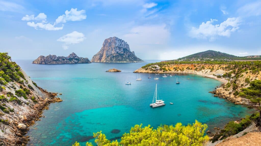 Vista de um mirante de Ibiza, com barcos no mar, rochas e montanhas