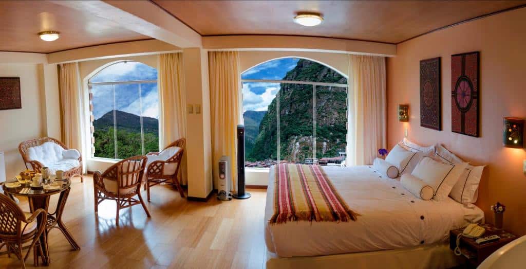 Quarto, com sala de estar e janelas com vista para as montanhas, do Hotel Taypikala Machupicchu