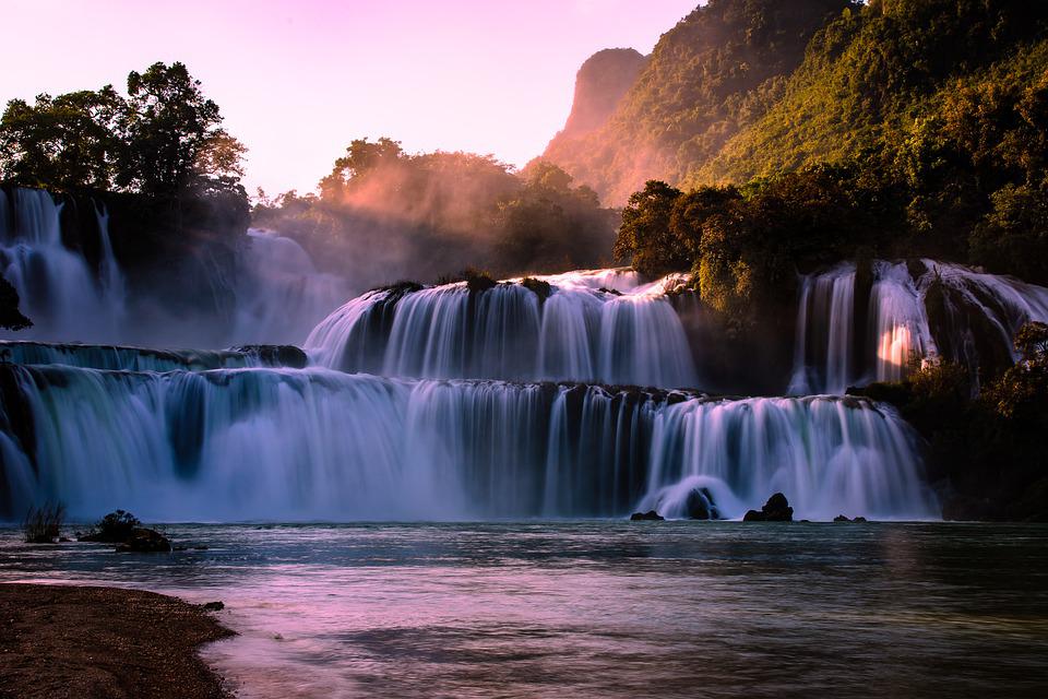 Várias quedas d'água chamadas Cachoeira Ban Gioc ao entardecer rodeadas de natureza no Vietnã