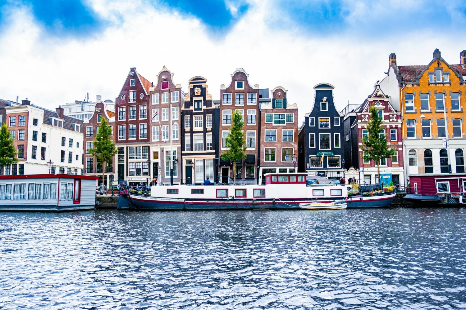 canal com barquinhos e casinhas coloridas em Amsterdã