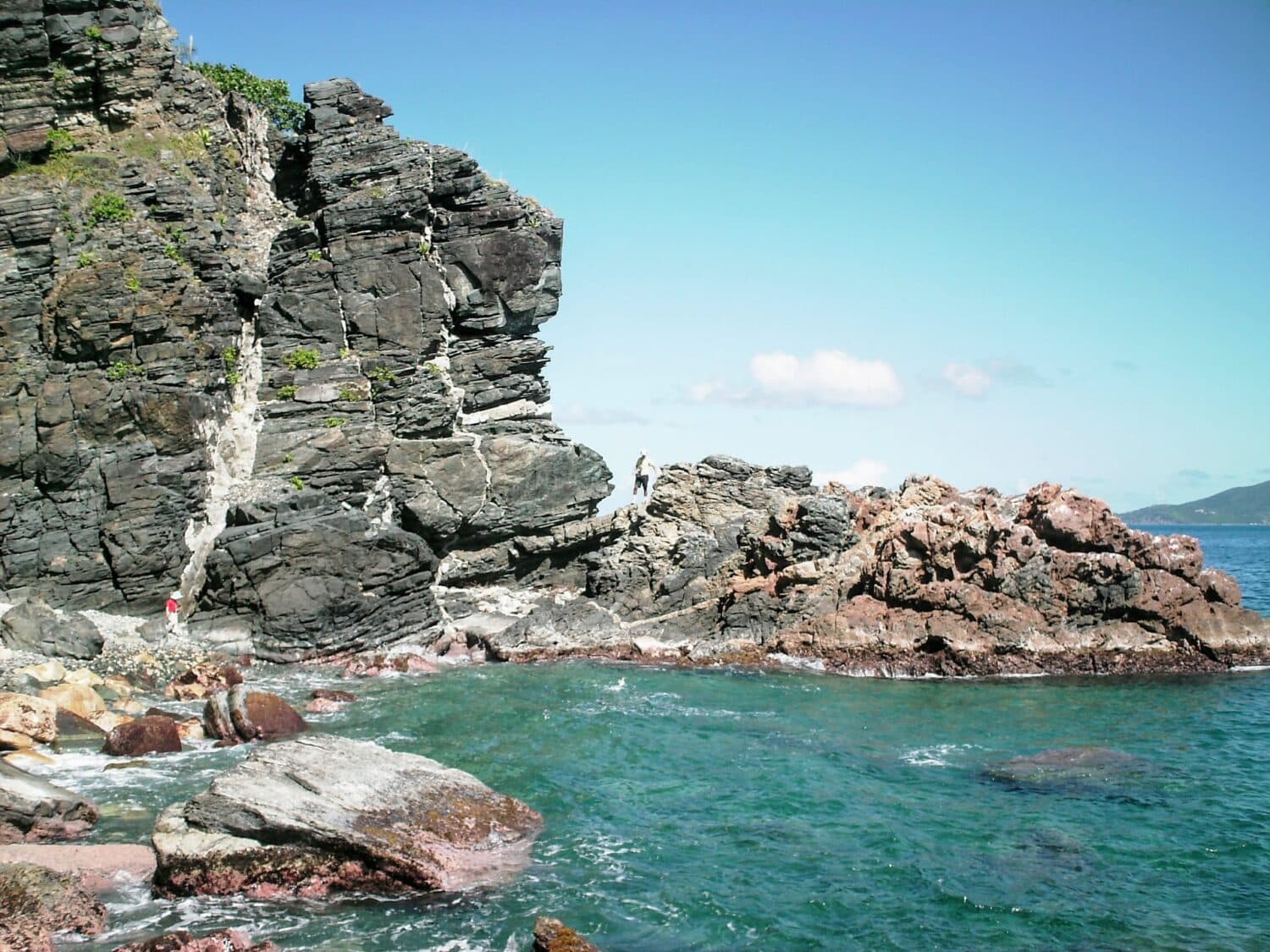 Muitas rochas formando um paredão contra a água transparente de Tortola em Ilhas Virgens Britânicas