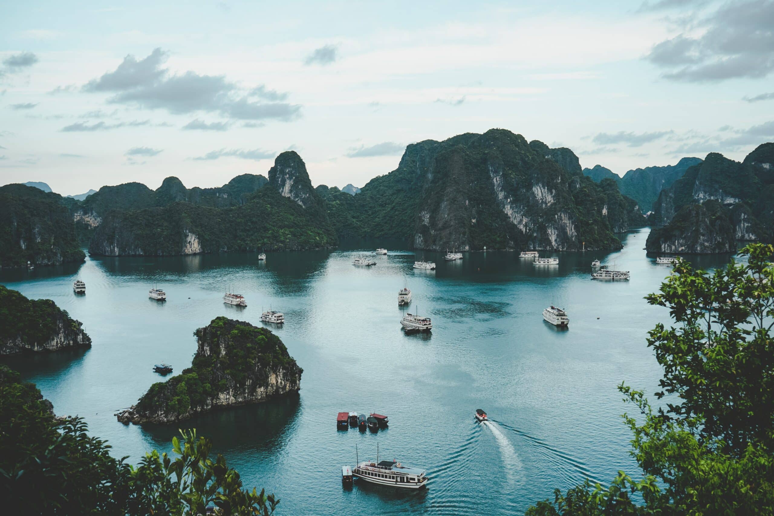montanhas vietnamitas rodeando a baía de Ha long com vários barcos e pescadores na água