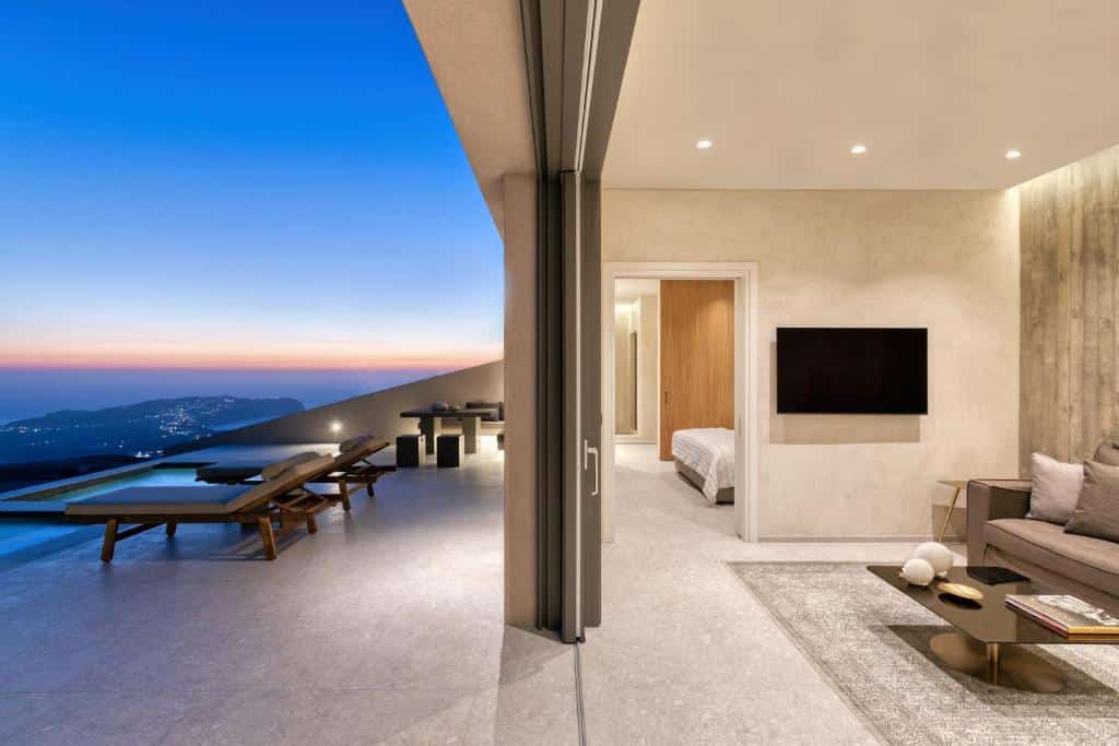 Parte da sala de estar, quarto e varanda com piscina particular e espreguiçadeiras do Santorini Sky Luxury Resort