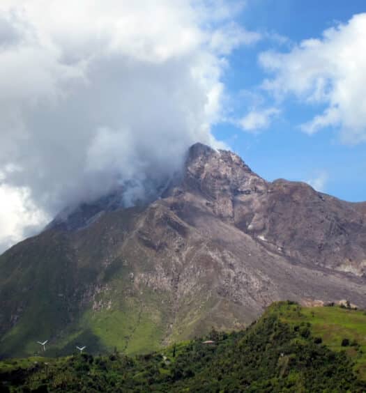 Soufrière Hill, o vulcão mais famoso de Montserrat, com muita vegetação ao pé dele e algumas nuvens nublando o topo do vulcão