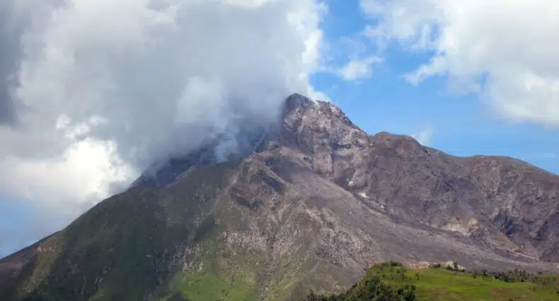 Soufrière Hill, o vulcão mais famoso de Montserrat, com muita vegetação ao pé dele e algumas nuvens nublando o topo do vulcão