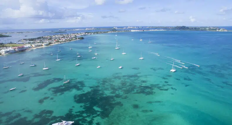 Vista de cima de uma região cheia de barcos em St Martin, o mar é tão claro que é possível ver as paredes de corais ao fundo
