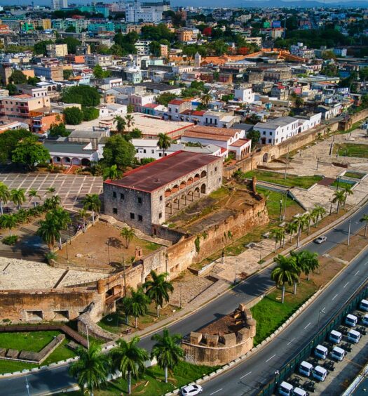 Zona Colonial em Santo Domingo, um local com prédios de arquitetura antiga, museus, uma estrada que beira o mar, muitas casas e vegetação ao redor