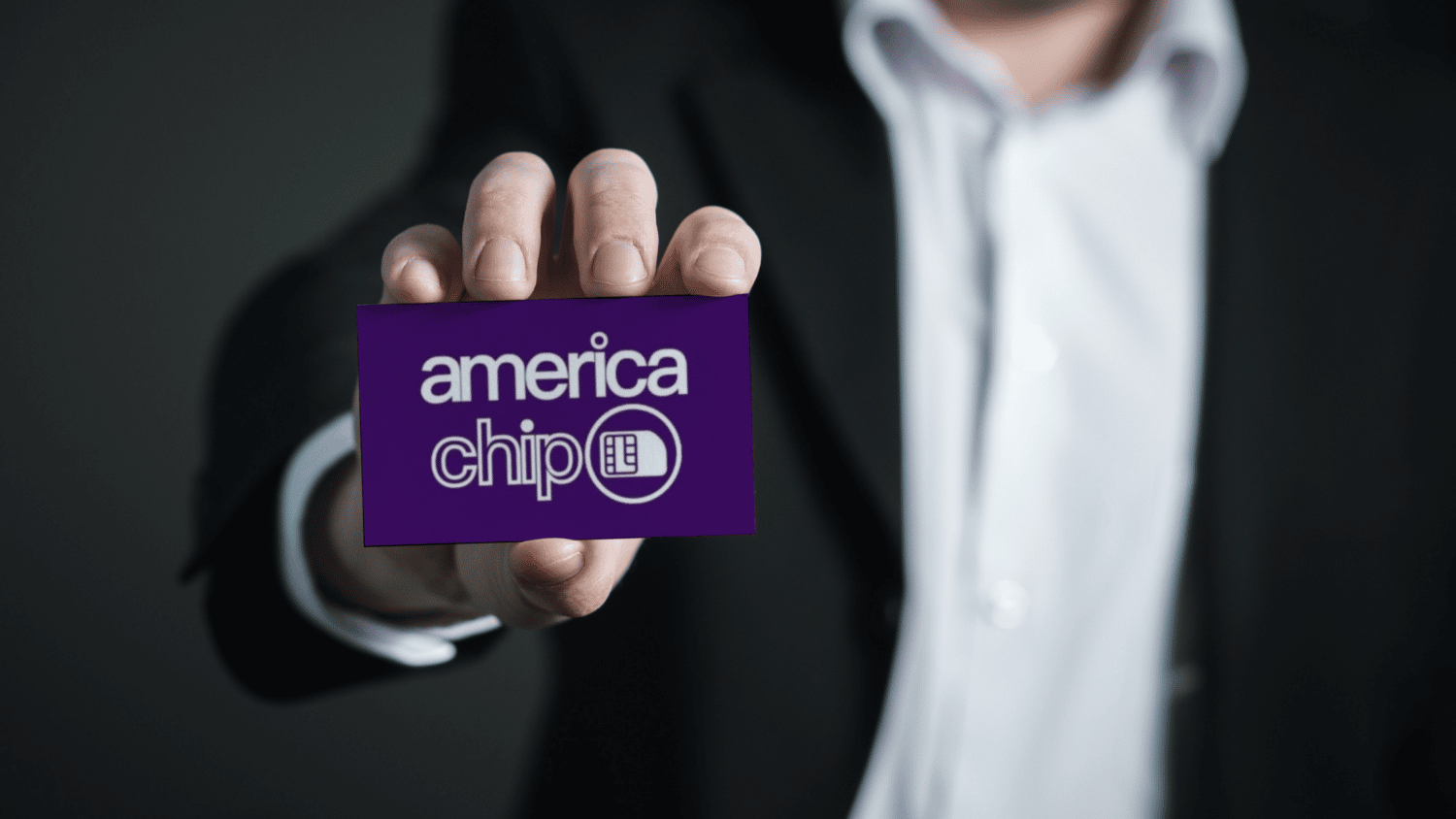 homem branco usando terno perto está com a mão estendida para frente, segurando um cartão com o logo da america chip