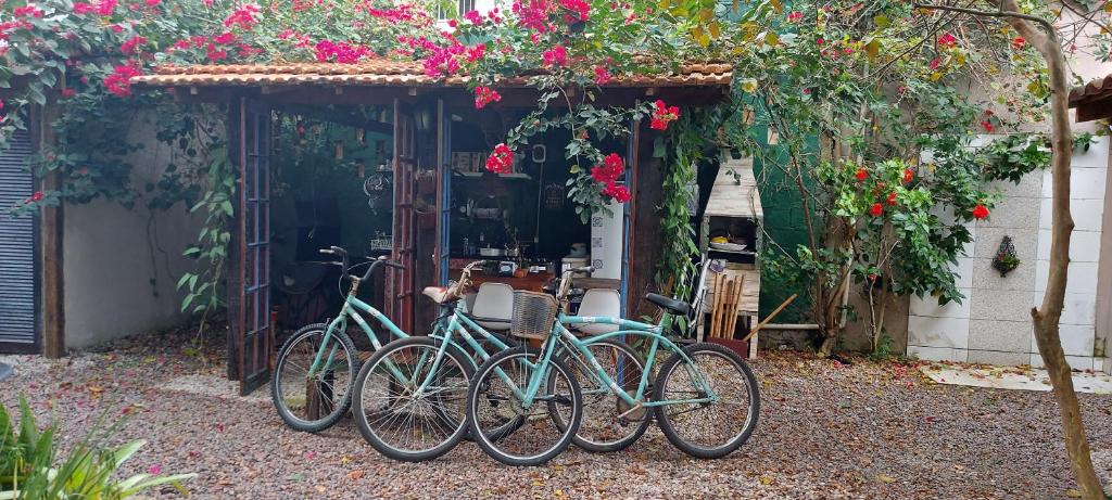 Parte do jardim da Casa Alma Zen - Hostel Boutique Ubatuba, com diversas bicicletas encostadas próximas de árvores e flores, e um chão de pedrinhas, para representar pousadas no Centro de Ubatuba