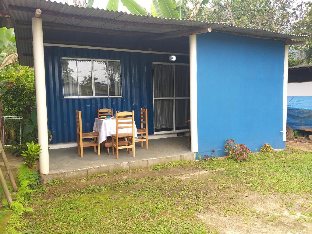 Entrada do Casa beira-mar em Praia do Ubatumirim, um container pintado de azul, com janela e porta de vidro, quatro cadeiras e uma mesão estão na pequena sacada