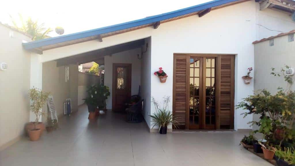 Quintal do Casa Centro De Ubatuba, espaço arejado, com uma jardim, vaso de flores, uma sacada com porta de madeira, para representar airbnb em Ubatuba