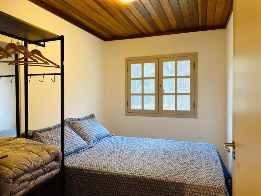 Quarto no Conforto e Paz na Natureza - Com WI-Fi, uma cama de casal, uma janela e um armário de conceito aberto, para representar airbnb em Campos do Jordão