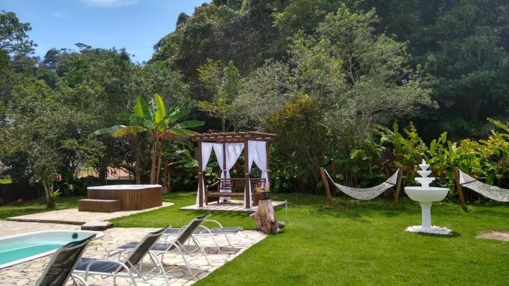 Jardim da Casa Pé na Areia em Ubatuba - Alto Padrão a 30m da Praia, com uma piscina, redes, espreguiçadeiras e um amplo jardim