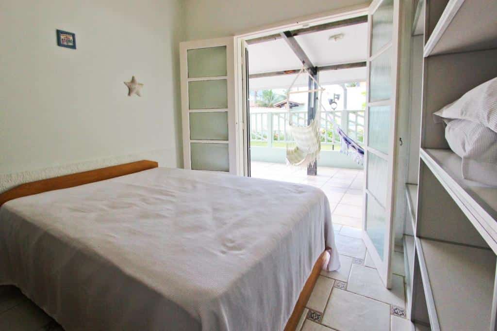 Quarto em  CASA TEMPORADA TUCO E TUCA, uma cama de casal com uma ampla varanda com redes penduras, uma armário aberto com travesseiros, para representar airbnb em Ubatuba