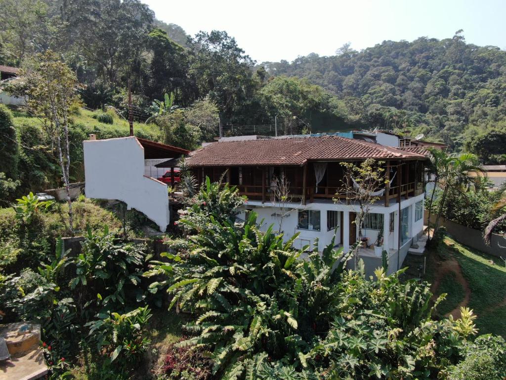 Imagem da Casa Ubatuba Vista para o Mar, com dois andares, cercada por árvores e montanhas