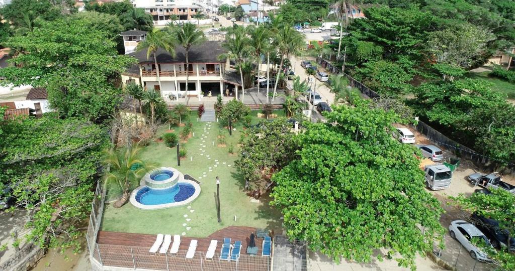 Vista área da Casa Vip Ubatuba - Vista para o Mar - Praia das Toninhas, um enorme gramado com uma piscina, uma casa de dois andares, algumas espreguiçadeiras, muitos coqueiros e, logo em seguida, a praia
