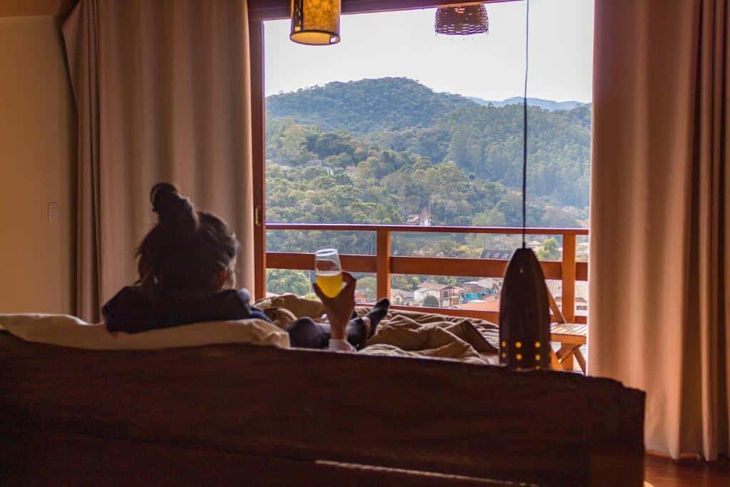 Pessoa sentada no sofá do Loft Maika'i, olhando para as paisagens de Santo Antônio do Pinhal