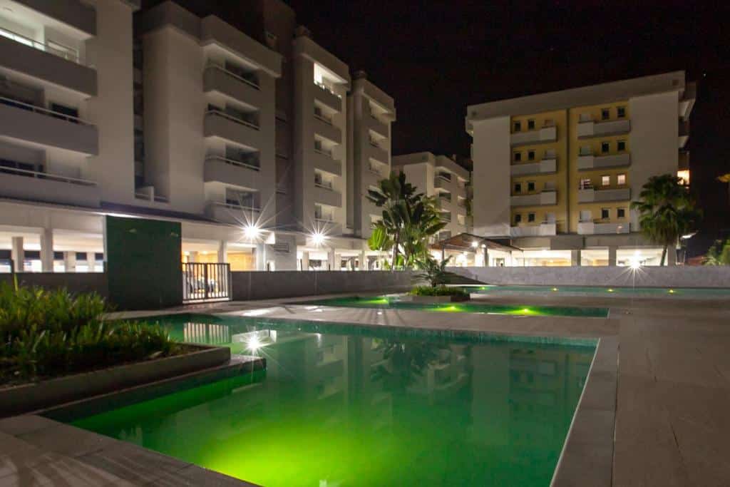 Piscina com iluminação verde de noite no Apartamento Ubatuba, AR, Varanda Gourmet, Piscinas e 300mt Praia