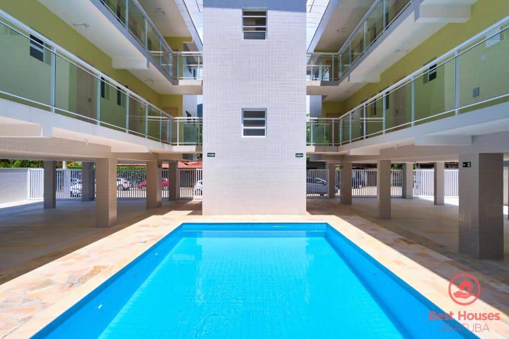 Piscina em Estúdios 3 Praias, a piscina no centro da foto, ao redor, é possível ver o estacionamento e as unidades de acomodação em formato de prédio