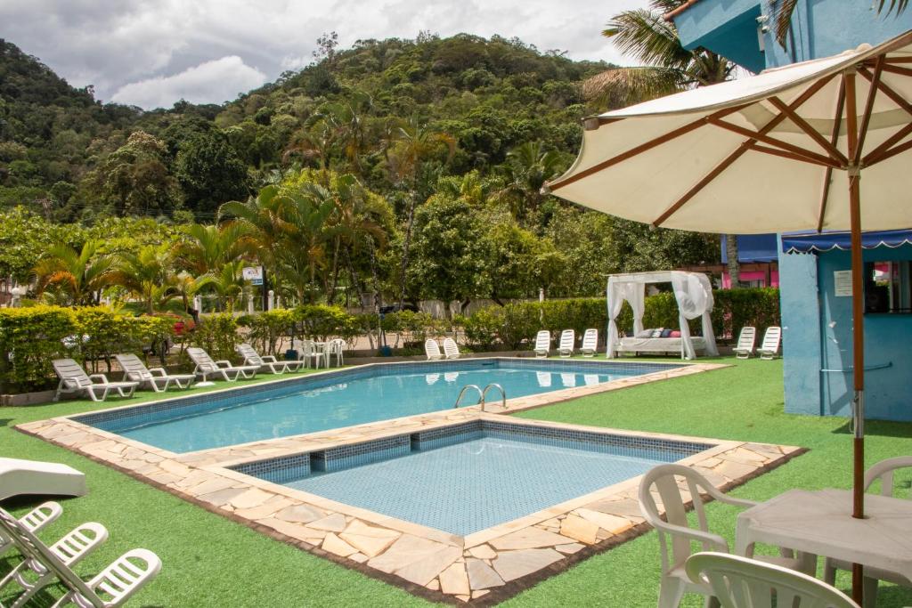 Piscina do Hotel Costa Azul, cercado por montanhas e muita natureza, com algumas espreguiçadeiras ao redor da piscina