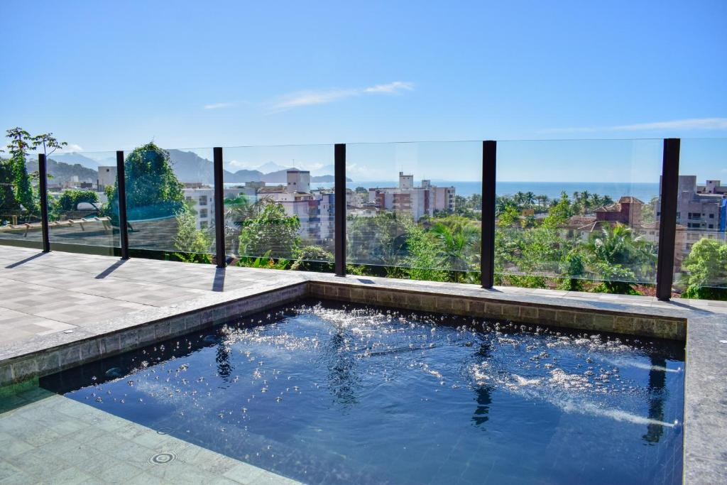 Piscina em Pousada Vista Dell Mar, uma piscina pequena com vista para os prédios, montanhas e a praia, para representar pousadas na Praia das Toninhas