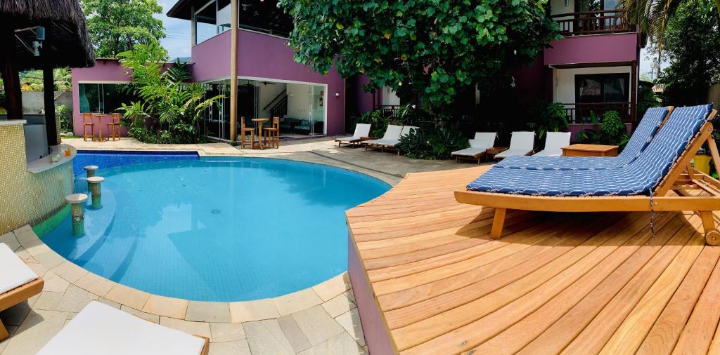 Piscina na Vila Bardot, uma piscina redonda com um bar perto, um deck com espreguiçadeiras e árvores ao redor