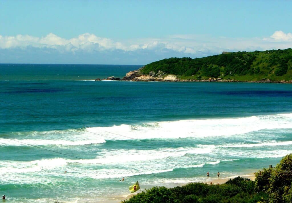 Vista da Praia do Rosa com mar azul.