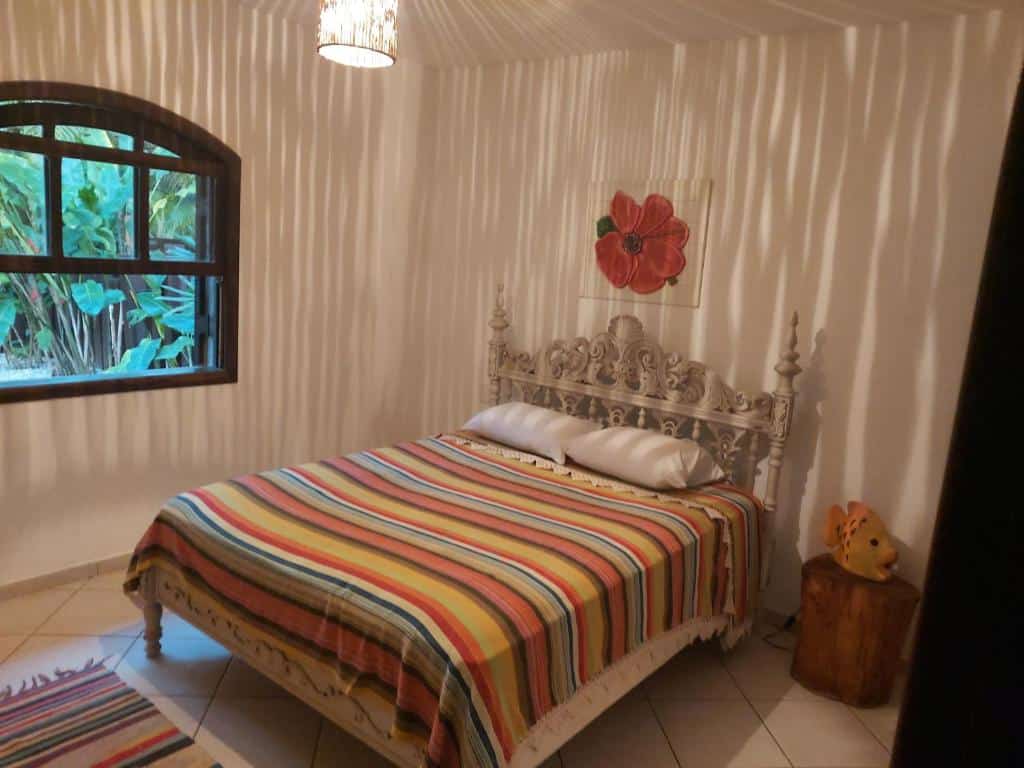 Quarto em Casa na praia de Itamambuca na cidade de Ubatuba, uma cama de casal, uma janela com vista para o jardim, ambiente decorado e novo, para representar airbnb em Ubatuba