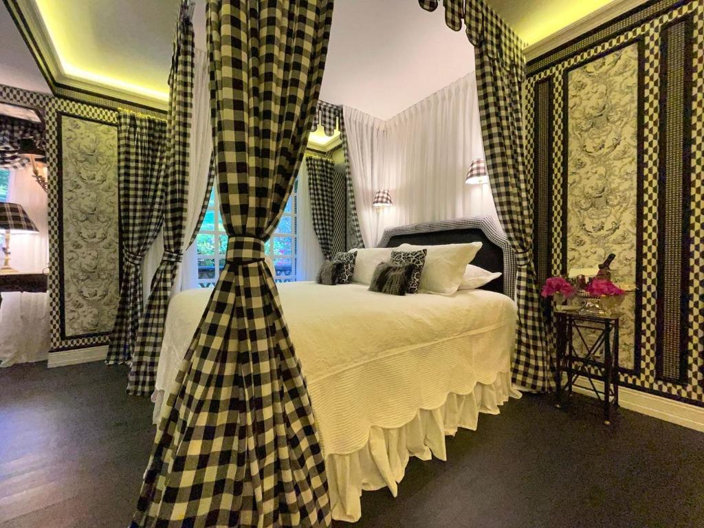 Quarto no Luar de Inverno 203 - Apartamento 3 suítes Gramado, tudo decorado em xadrez e flores em preto e branco, cama de casal, dois abajures e uma sacada, para representar airbnb em Gramado