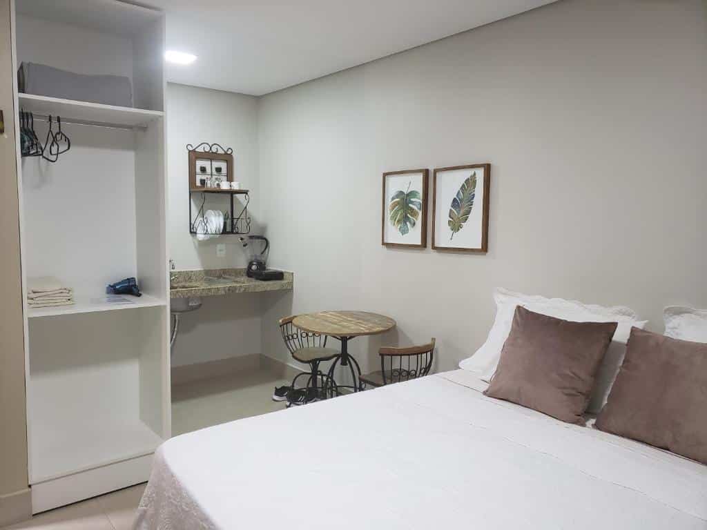 quarto da Pousada das Orquídeas com uma cama de casal, uma mesa com duas cadeiras e uma cozinha funcional
