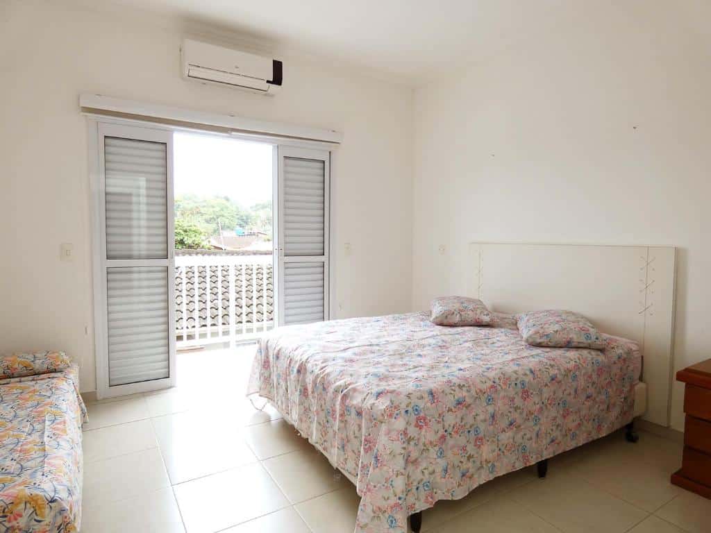 Quarto em Sobrado c lazer e wifi a 5 min da praia em Ubatuba, uma cama de casal, uma varanda, um ar-condicionado e uma cama de solteiro, para representar airbnb na Praia do Lázaro