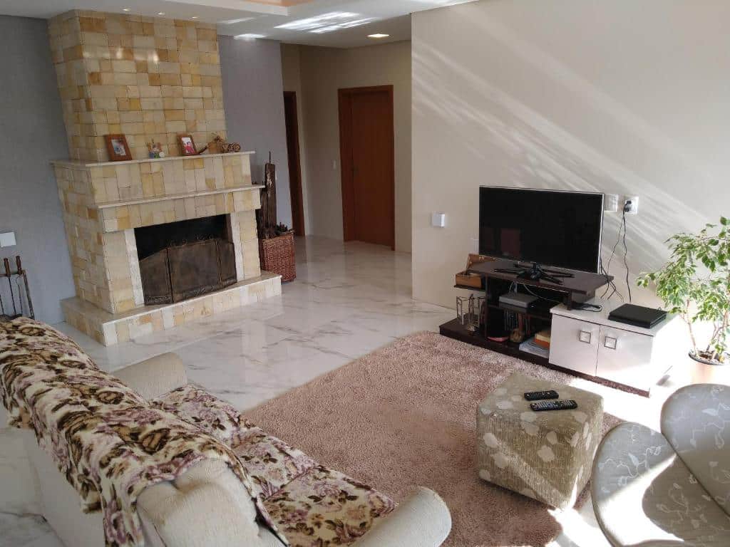Sala da Casa Gramado - Moradas da Serra, uma lareira, dois sofás, uma televisão, local bem amplo, para presentar airbnb em Gramado
