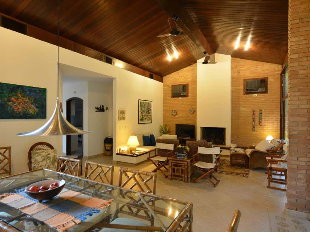 Sala de estar e de televisão em Casa Pérola, ambiente amplo, com ar-condicionado, sofás, cadeiras, mesa de jantar, alguns enfeites rústicos, para representar airbnb na Praia do Lázaro