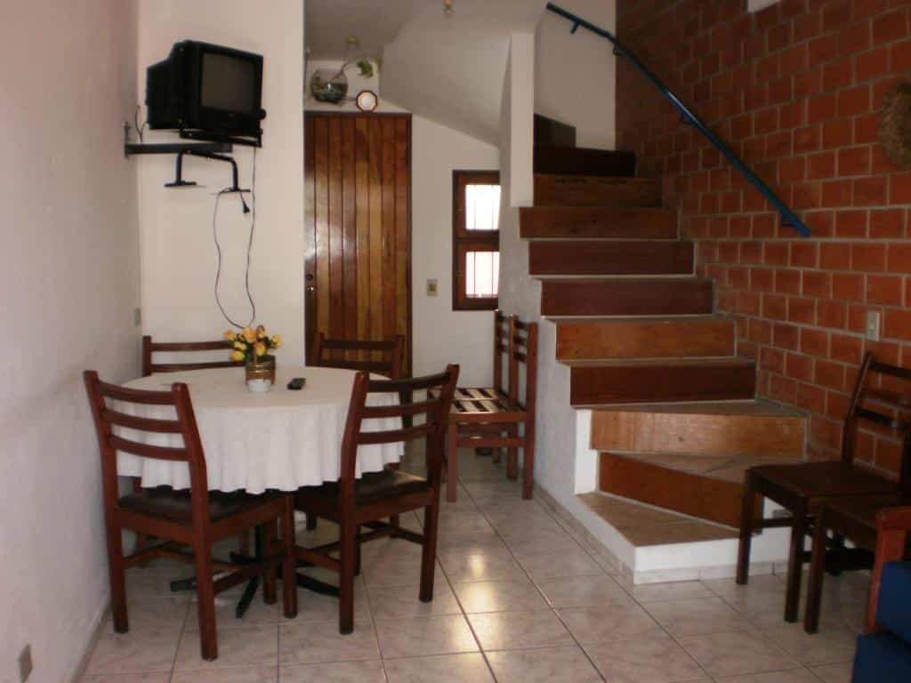Vista da sala, com escada, mesa e Tv na Sol e Cia casa de temporada, na praia de Tabatinga.