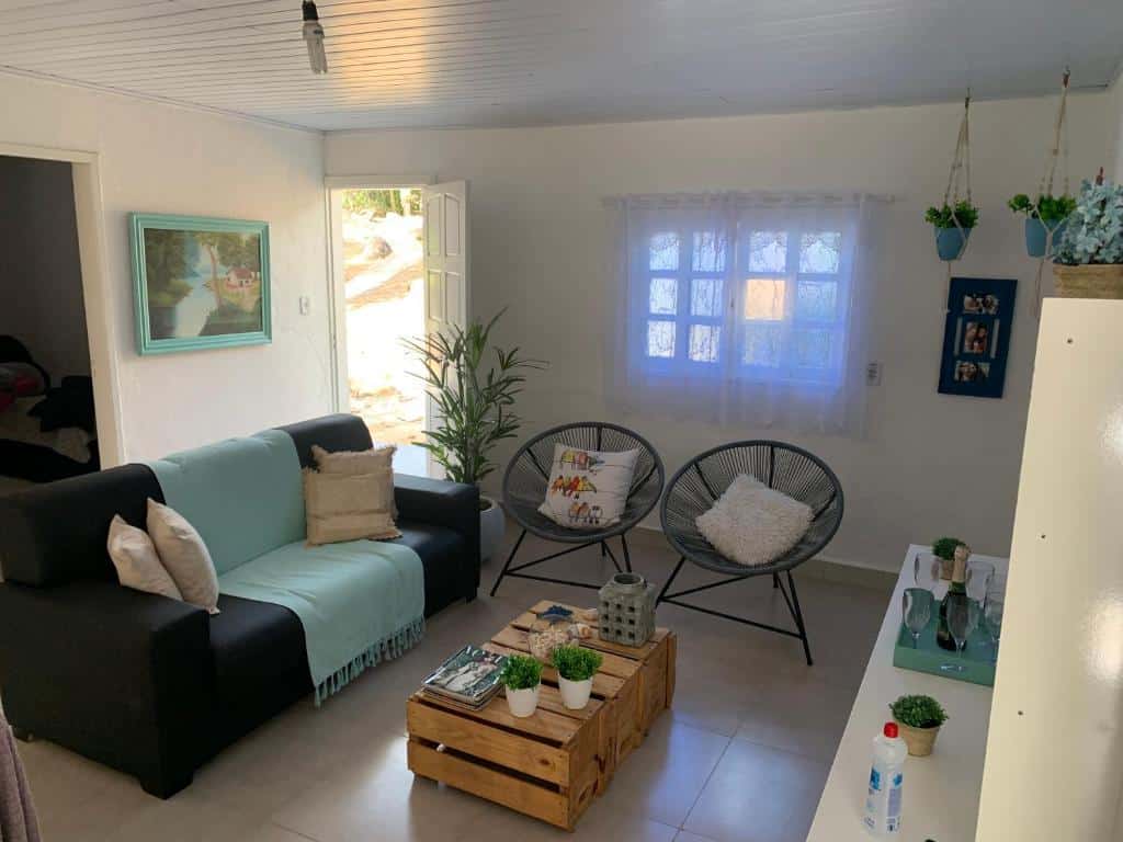 Sala de estar da Thabi's House Prumirim, um sofá, duas poltronas, uma mesa de centro de madeira, decoração em tons de azul, para representar airbnb em Ubatuba