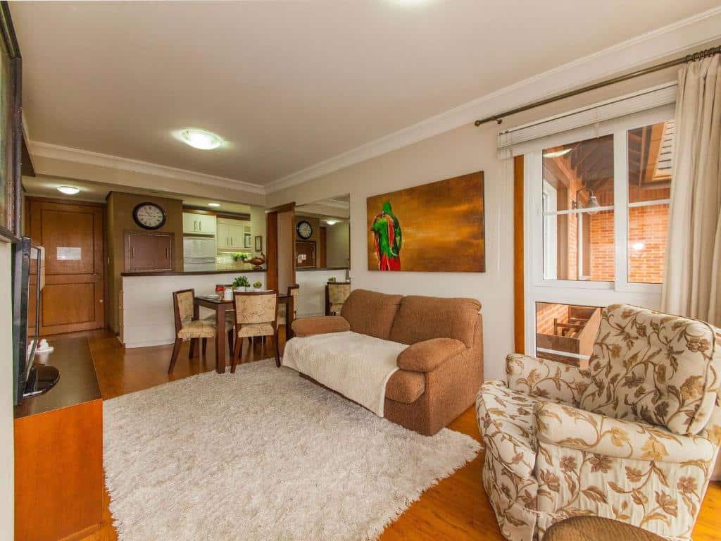 Sala de estar na Villa Di Pietro - 404, um tapete, um sofá, uma poltrona, uma mesa com quatro lugares, tudo decorado em tons de marrom e bege