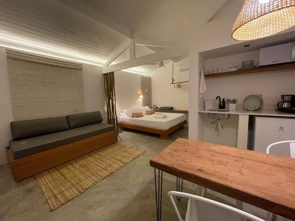 Ambiente completo da  Villa Tennis, um estúdio com uma cama de casal, um sofá amplo, uma janela, uma sacada, um mini cozinha, uma mesa e cadeiras, para representar airbnb em Ubatuba