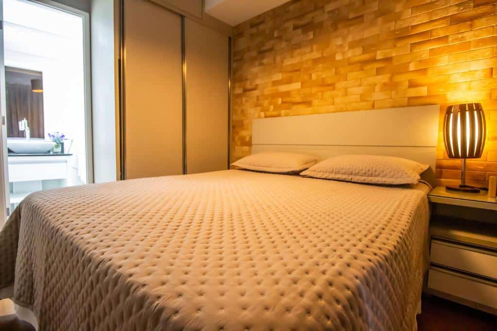 Quarto com uma cama, e banheiro com a porta aberta mostrando apenas a pia de um dos airbnb em São Paulo