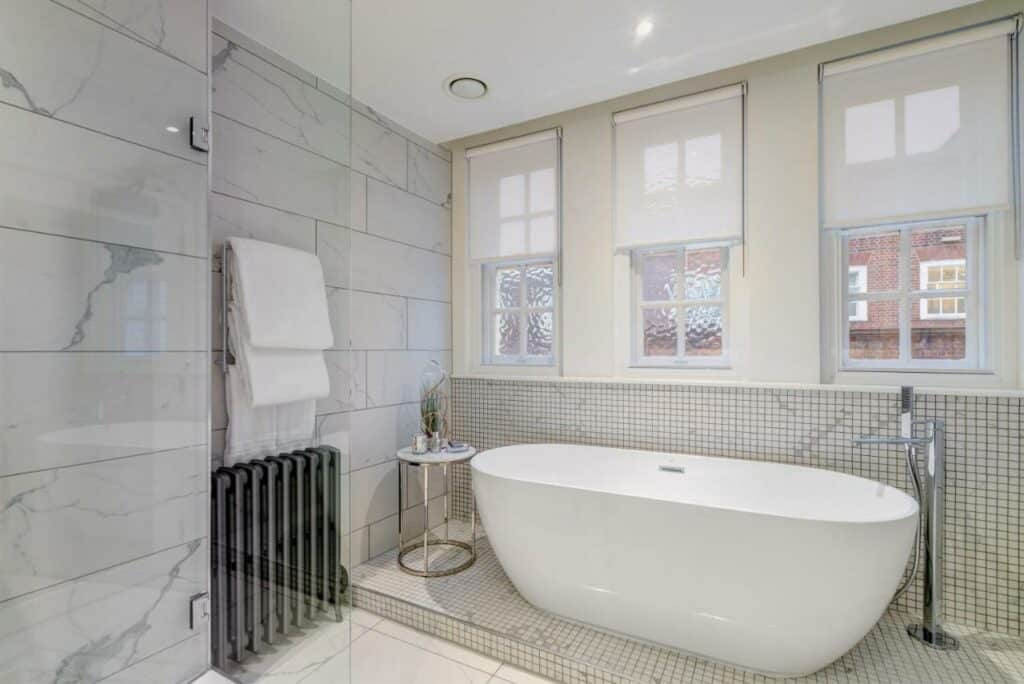 Banheiro muito amplo no Apex Temple Court Hotel com uma banheira, três janelas e toalhas a disposição, para representar hotéis em Londres