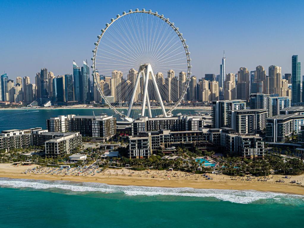 Vista do Caesars Palace Dubai, localizado em uma região costeira do mar, com prédios em volta e roda gigante