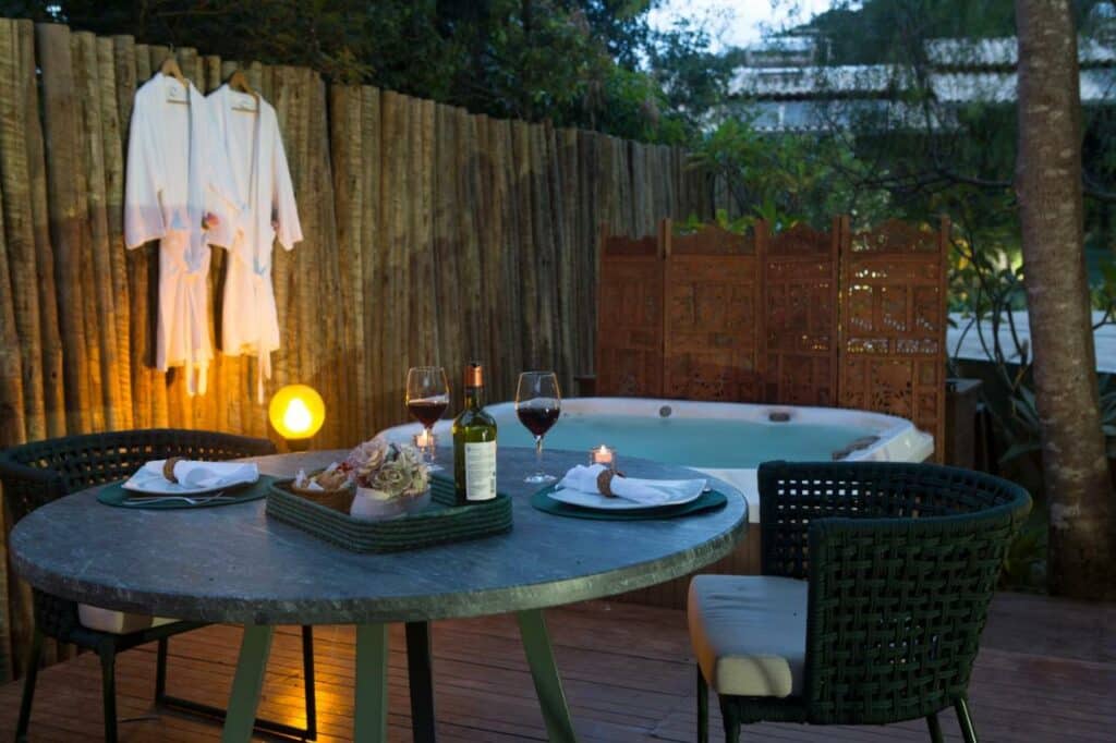 Casa da Lua Pousada com uma banheira de hidromassagem ao ar livre, com roupões ao lado, e uma mesa com dois lugares com taças de vinho