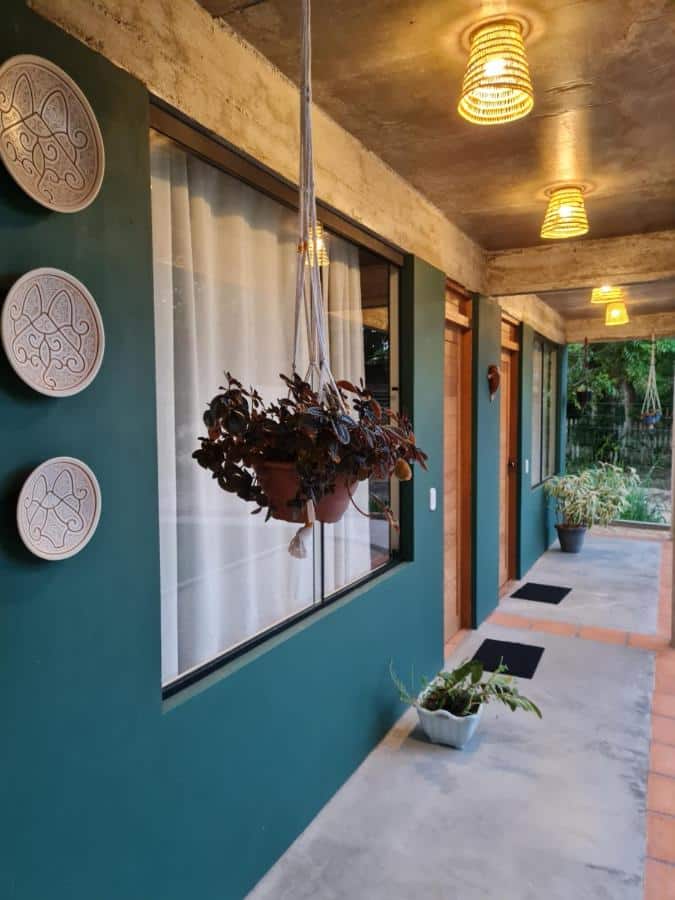 Hall para os quartos na Casa Saimiri com decoração rústica e plantas penduradas