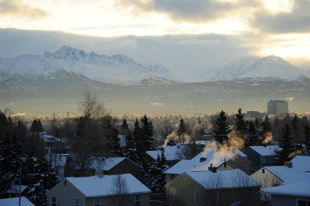 Cidade de Anchorage no Alaska com casas cobertas pela neve e ao fundo uma montanha coberta de neve.