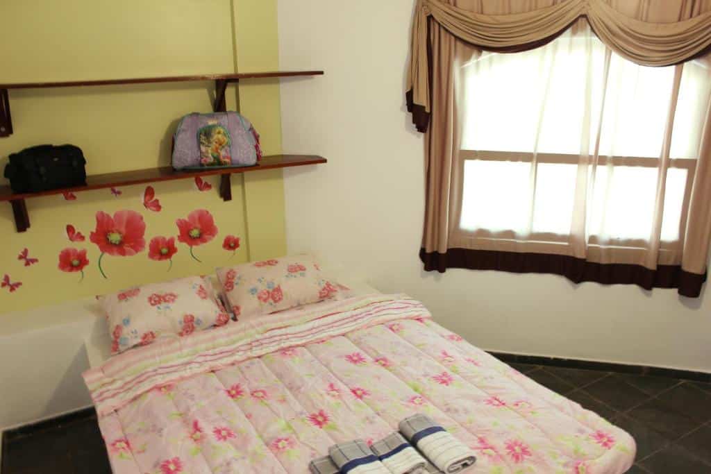 Quarto com cama de casal no Farol das Gaivotas Pousada e Residente, iluminado naturalmente por uma janela ampla com cortina voil
