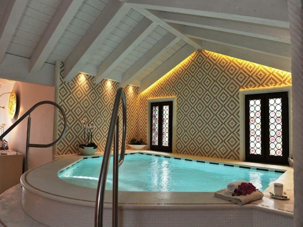 Uma banheira de hidromassagem ampla e coberta no Hotel Ai Reali com vasos de flores ao redor