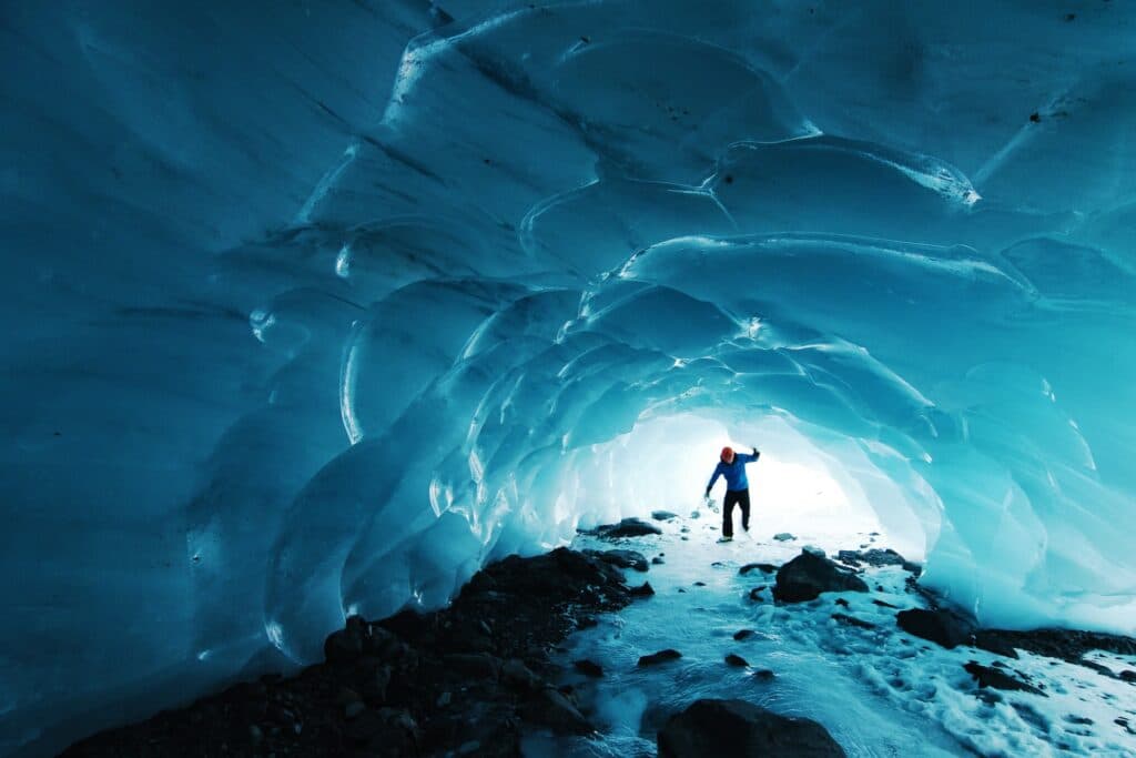imagem de um homem entrando em uma caverna glacial em Chugach National Forest no Alaska.